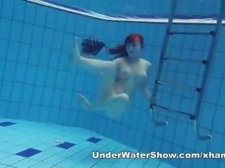 Redheaded deity swimming nude in the pool
